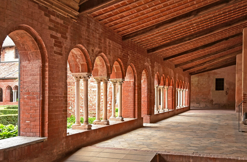 chiostro interno dell'abbazia di Staffarda, cono colonne in controluce e mattoni.