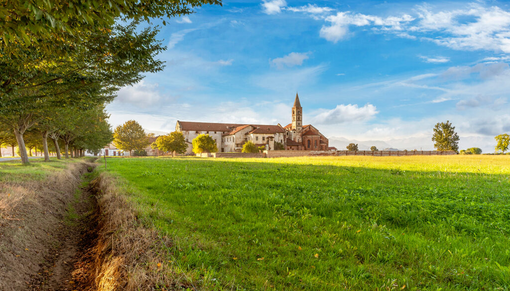 Visuale della campagna in estate, con cielo sereno e l'abbazia di Staffarda a circa 150 metri.