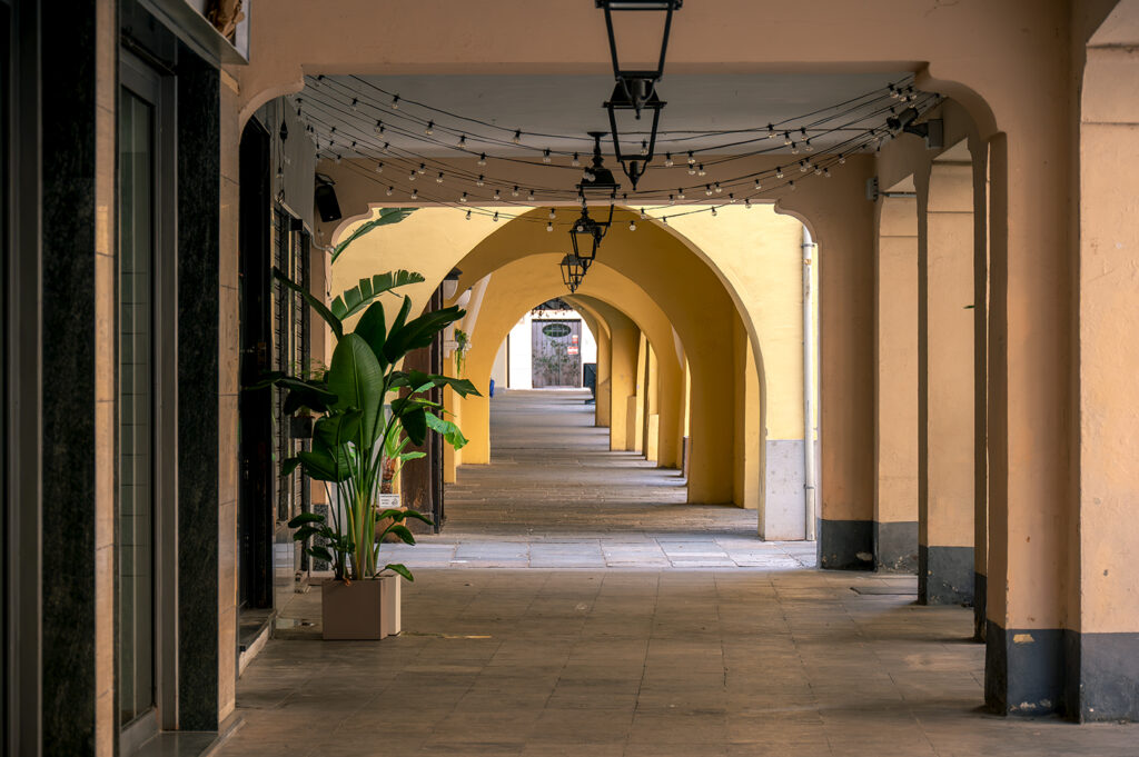 Foto che inquadra una lunga serie di portici, con leggero gioco di ombre e prospettiva.