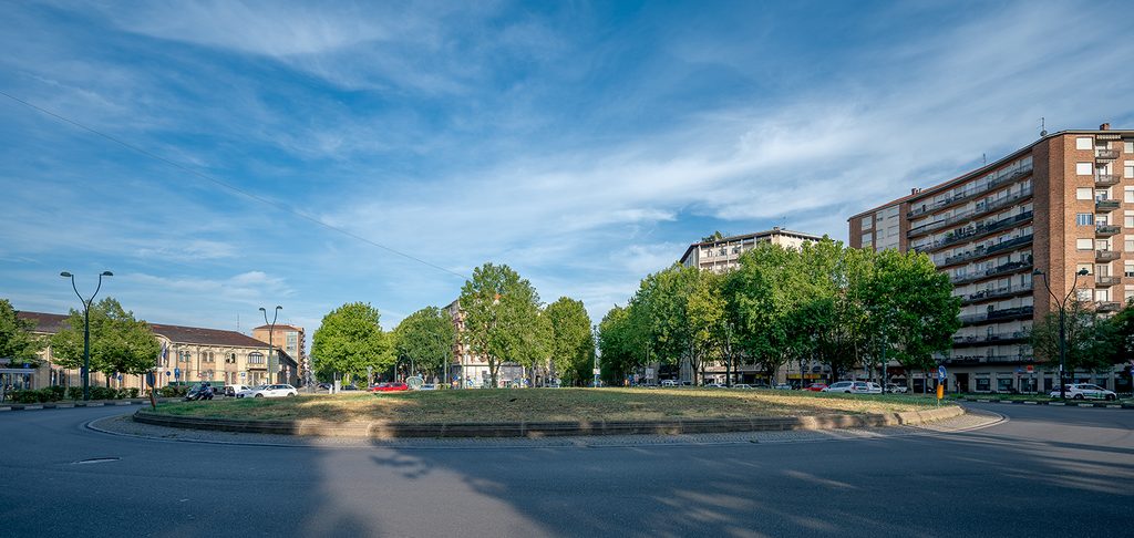 Visuale di piazza Rivoli a Torino, in un giorno d'estate con cielo azzzurro, rotonda ed edifici circostanti.