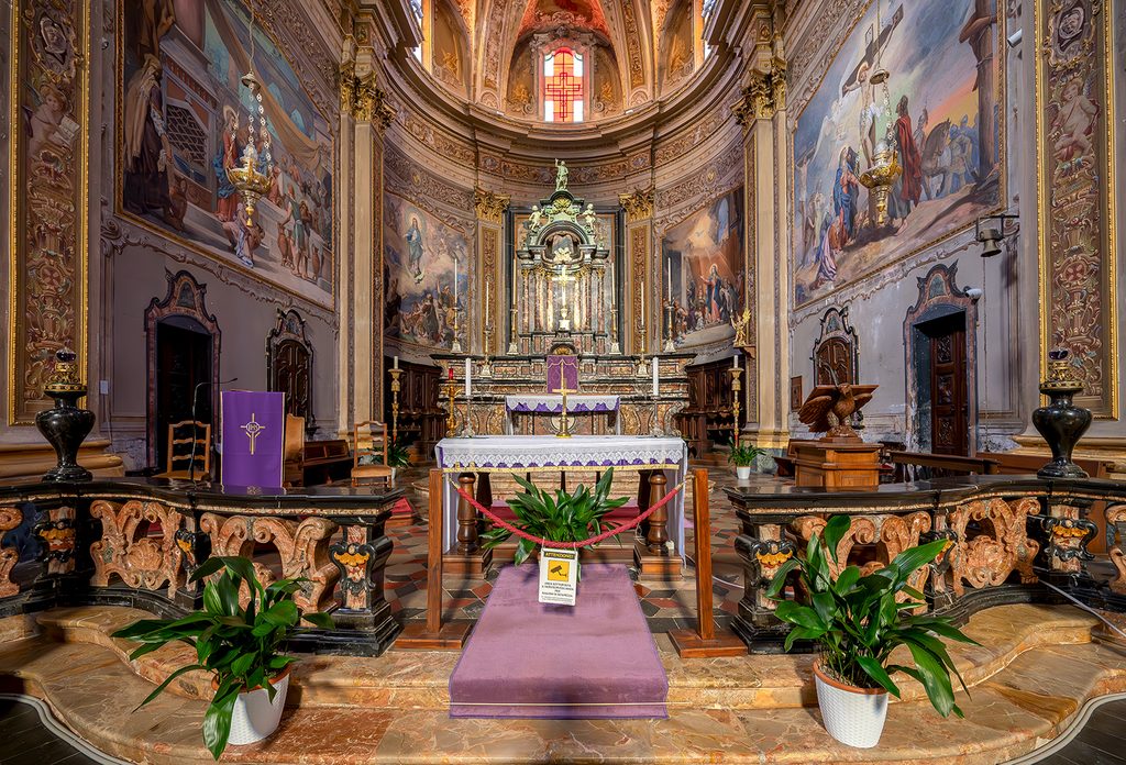 Primo piano dell'altare maggiore, con decorazioni e dipinti alla pareti del presbiterio.