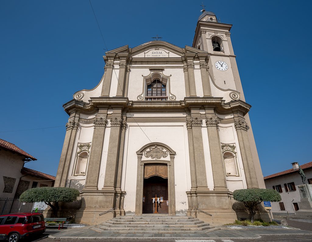 Facciata della chiesa di Santa Maria Assunta a Carpignano Sesia, con campanile e cielo azzurro sereno